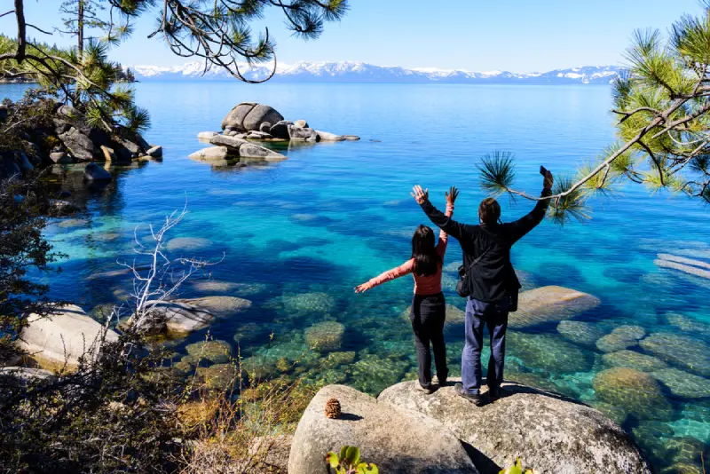 happy couple stands on the rocks_1974745196 A happy couple stands on the rocks on the shore of Lake Tahoe.