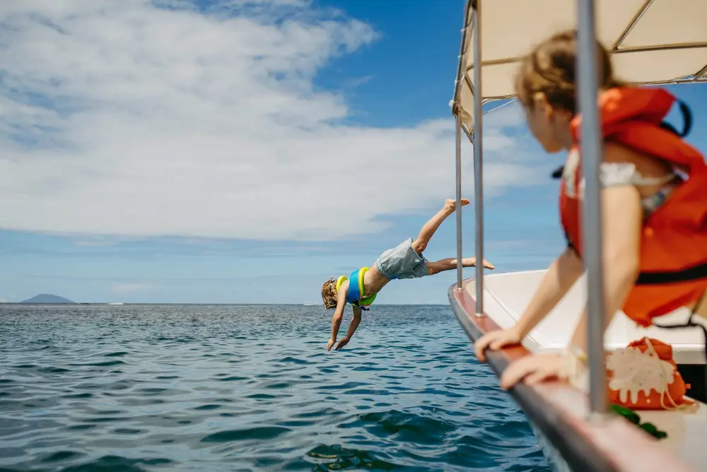 A child jumps off a boat and into the water.