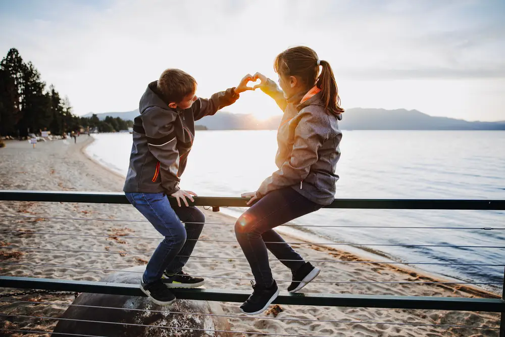 brother and sister make a heart with their hands_1712807335 A brother and sister make a heart with their hands while on vacation at the lake.